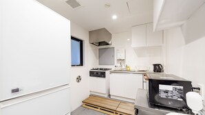 Una cocina compacta con gabinetes blancos, estufa, fregadero y cafetera.