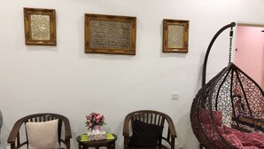 Una stanza con tre sedie di legno, un tavolino con un vaso di fiori e una poltrona a dondolo.