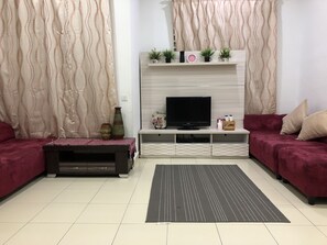 A modern living room with a TV, sofa, and decorative items. - Seri Rendang Homestay Pekan Pahang (Pekan)