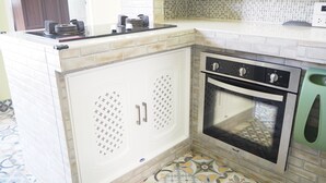A kitchen with a built-in oven, a sink, and a tiled backsplash. - Baan Tukta (Cha-am)
