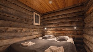 Un dormitorio tipo cabaña de madera con una cama, almohadas y un cuadro en la pared.