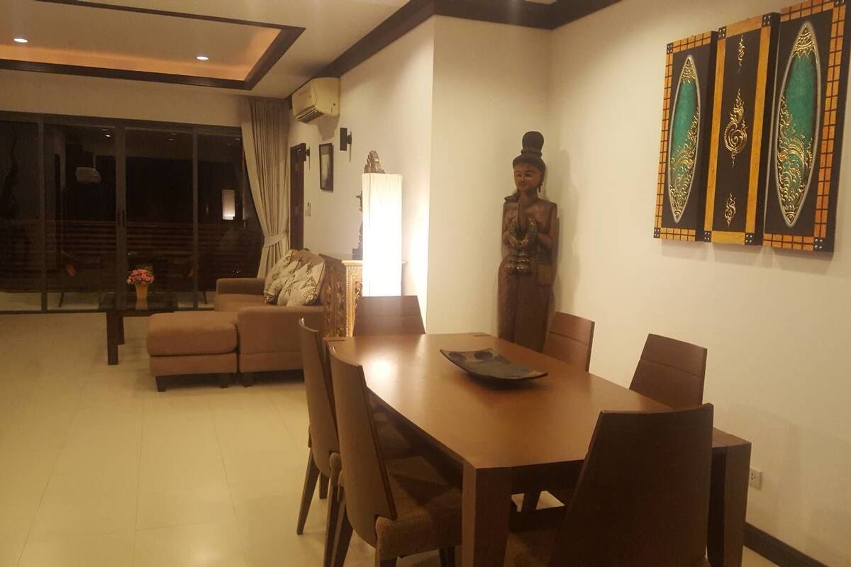 A dining area with a wooden table and chairs, a statue, and a decorative panel on the wall.