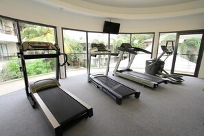 Un gimnasio con cintas de correr, una bicicleta estática y un banco de pesas.