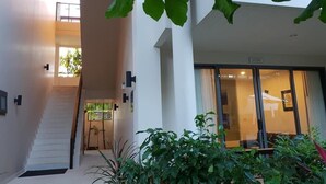 A modern building with a staircase leading to an upper floor, a glass door entrance, and indoor plants. - TSE Residence by Samui Emerald Condominiums (Koh Samui)