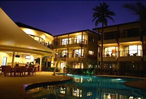 Un hotel con piscina, varios balcones y una zona de bar.