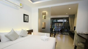 A hotel room with a large bed, a desk, and a view of the outdoor area. - TSE Residence by Samui Emerald Condominiums (Koh Samui)