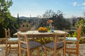 A wooden table with chairs, a basket of lemons, a vase with flowers, and a lantern. - Agroturismo Can Prats (Santa Eulalia del Rio)