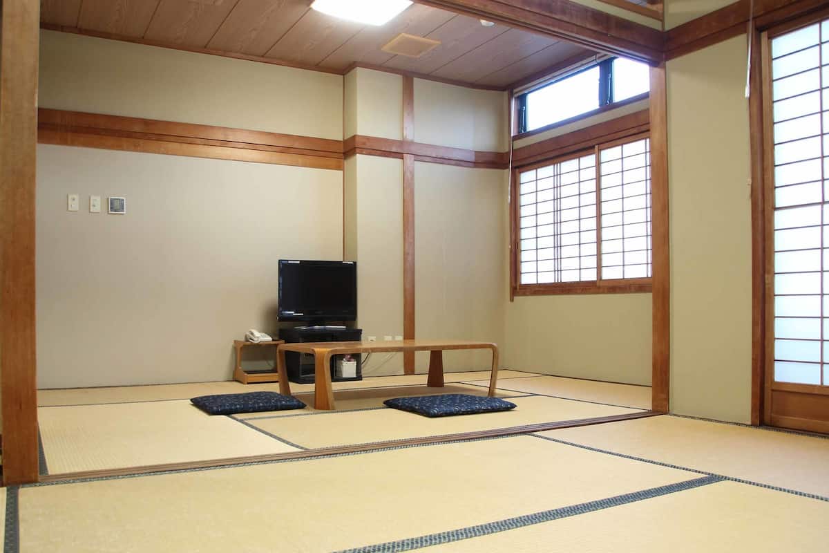 A traditional Japanese room with tatami flooring, a television, and a small table.