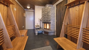 Un intérieur en bois avec une cheminée en pierre, des bancs et une porte.