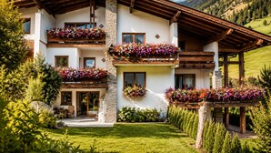 Ein mehrstöckiges Gebäude mit Balkonen, die mit Blumen geschmückt sind, einer Steinfassade und einem Holzdach.