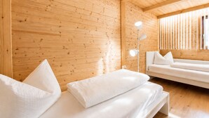 Ein Holzblockhaus-Innenraum mit einem Bett, einer Couch und einer Stehlampe.