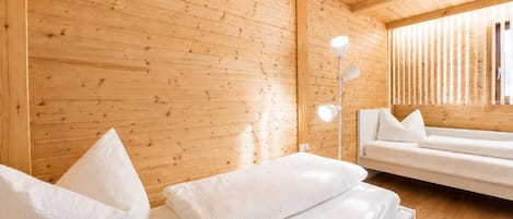 A wooden cabin interior with a bed, a sofa, and a floor lamp.