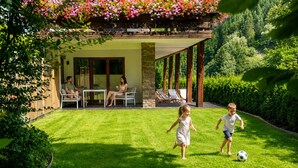 Ein Wohnhaus mit Terrasse, Gartenmöbeln und einem gepflegten Rasen.
