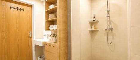 A bathroom with a wooden vanity, a shower, and a toilet.