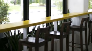 A modern interior with a long table and chairs, large windows with black frames, and hanging light fixtures. - Yaks House Hostel (Bangkok)