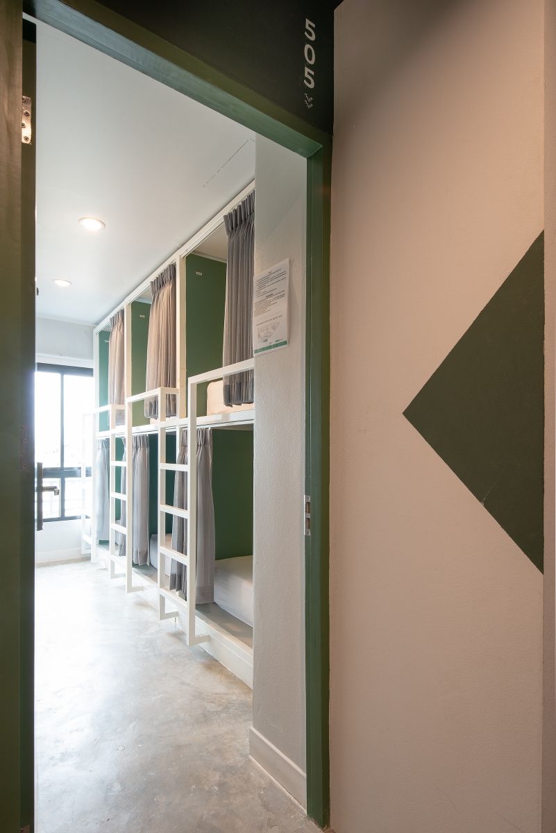 A hotel room with bunk beds, a green accent wall, and a door leading to another room.