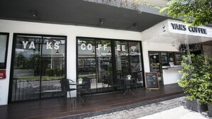 A coffee shop named Yaks Coffee with outdoor seating and a chalkboard menu. - Yaks House Hostel (Bangkok)