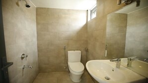 Un baño con azulejos color beige, un inodoro, un lavabo y un espejo.