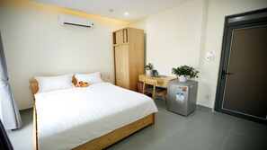 Una camera da letto con un letto, una scrivania, un armadio, un frigorifero e una porta.