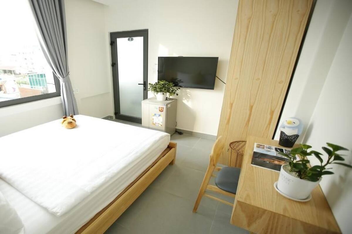 Ein Hotelzimmer mit Bett, Schreibtisch, Stuhl, Fernseher an der Wand und einem Fenster mit Vorhängen.