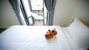 Una cama con sábanas blancas y un peluche.