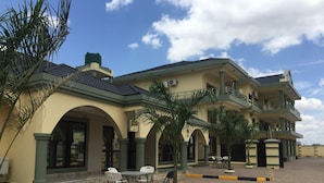 A multi-story hotel with a courtyard featuring outdoor seating and palm trees. - The Prince Charles Hotel (Lusaka)
