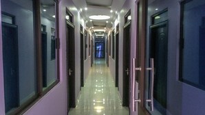 A long, narrow hallway with doors on both sides, leading to rooms. The floor is shiny and reflective. - The Prince Charles Hotel (Lusaka)