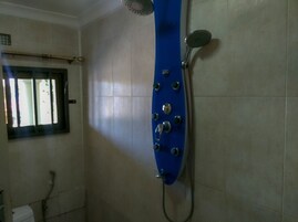 Un baño con ducha, ventana y paredes de azulejos.