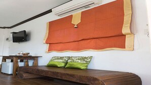 A room with a wooden bench, a television on the wall, and a large orange and beige curtain. - Keawanongburi Resort (Nakhon Ratchasima)