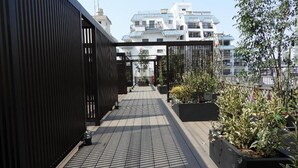 A rooftop terrace with a wooden floor, black metal railings, and potted plants. - Act Hotel Roppongi (Tokyo)
