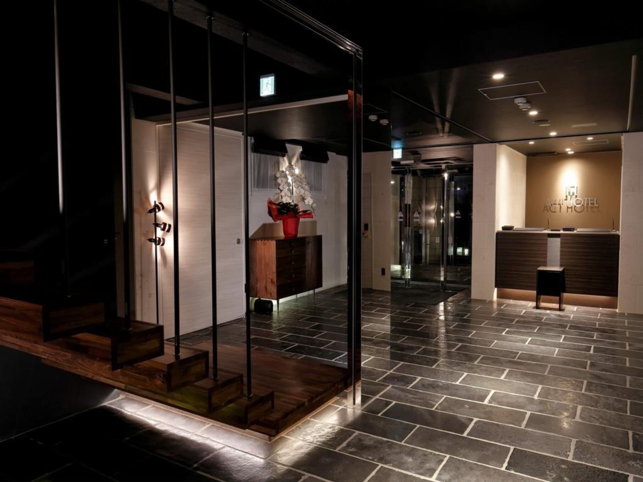A hotel lobby with a reception desk, a staircase, and a modern interior design.