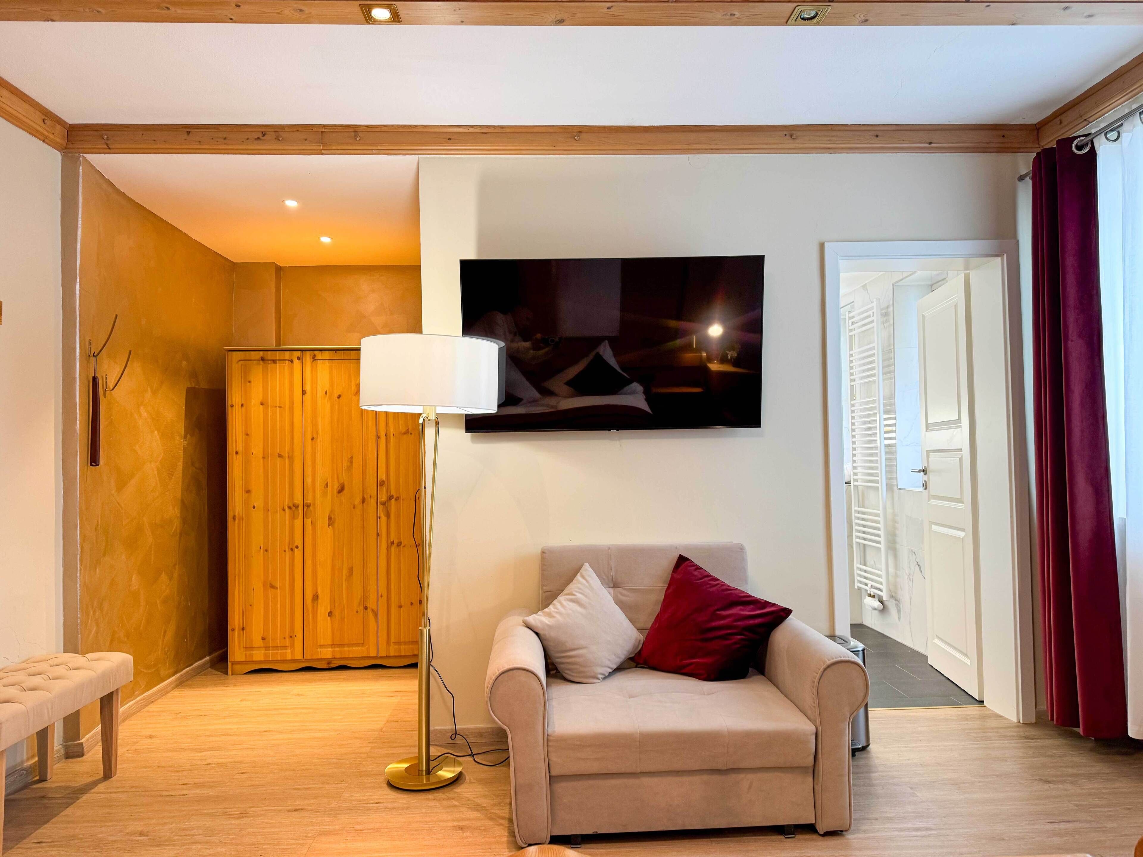 Ein gemütliches Wohnzimmer mit einem beigefarbenen Sofa, einer Stehlampe und einem Holzschrank.