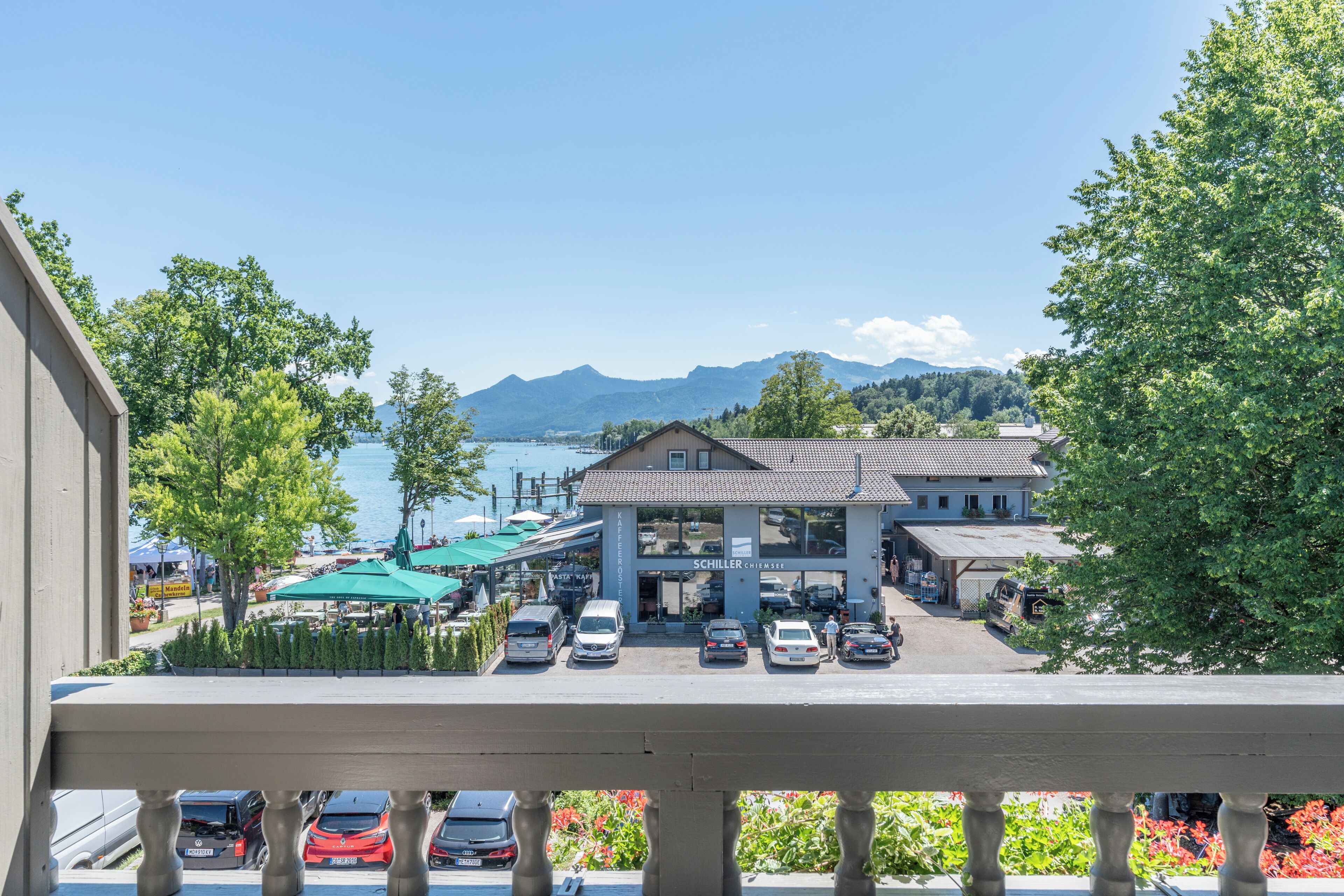 Un hotel con estacionamiento, asientos al aire libre y vistas a un lago y montañas.