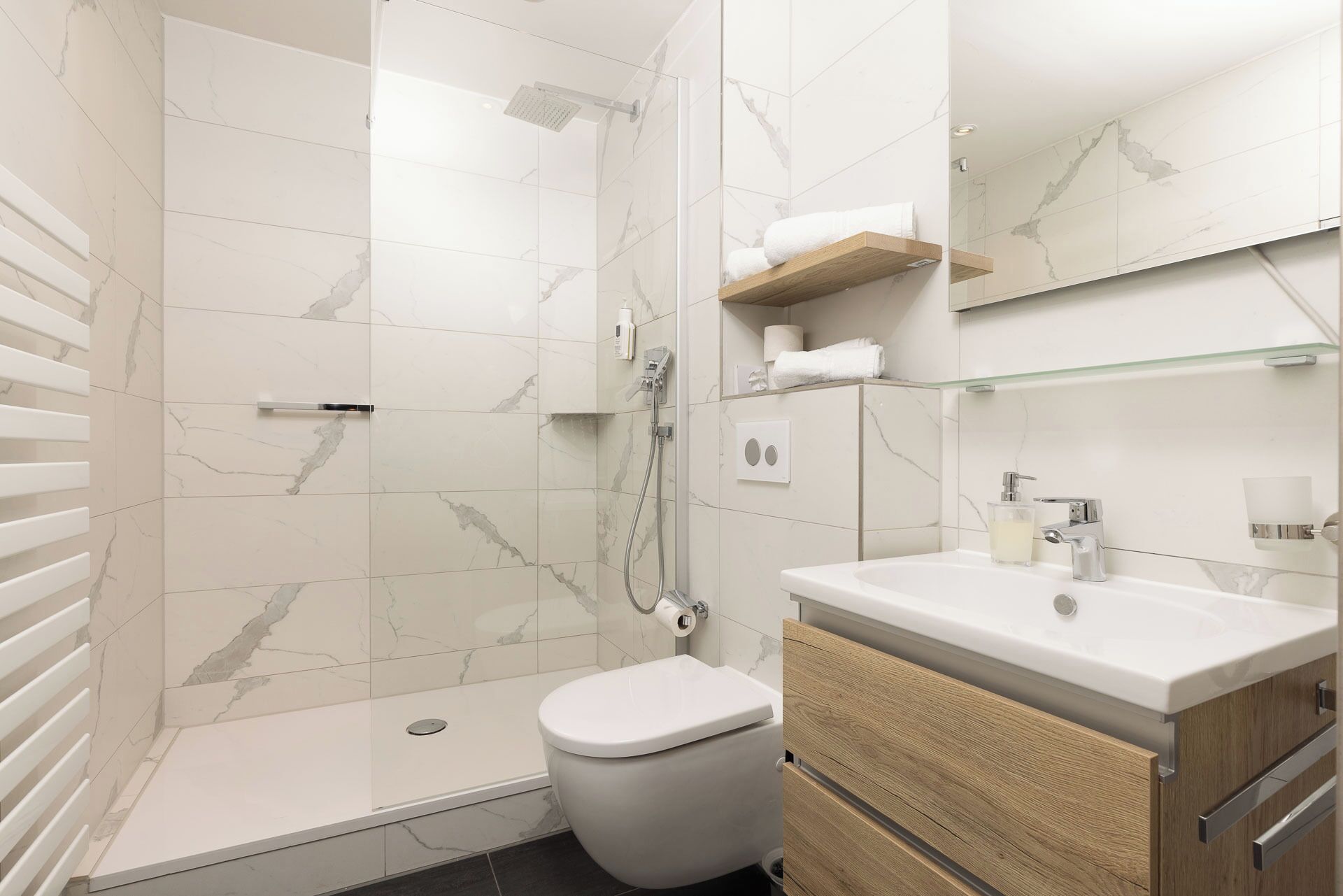 Et moderne badeværelse med bruser, toilet og vaskemøbel.
