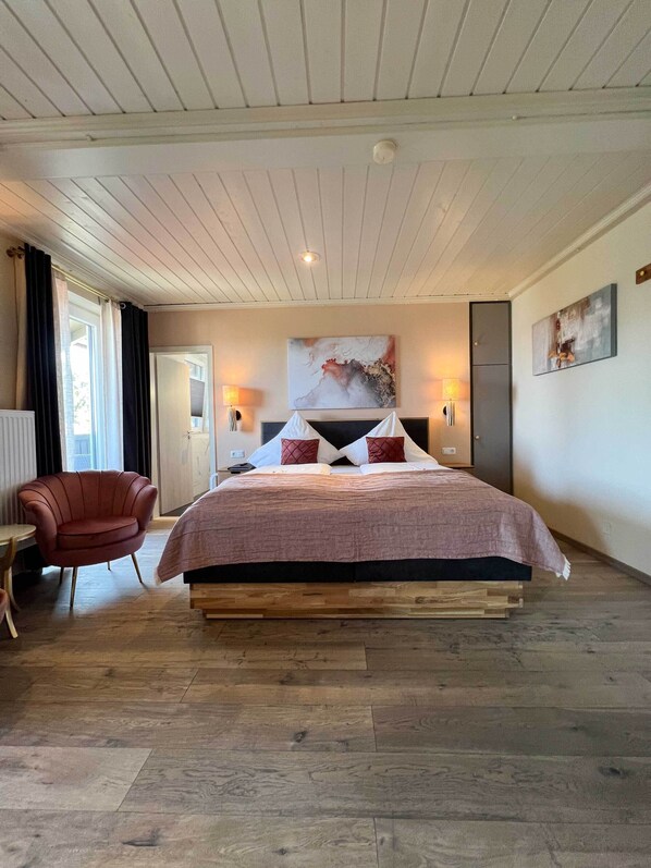 Un dormitorio con una cama grande, una silla, un escritorio y un cuadro en la pared.
