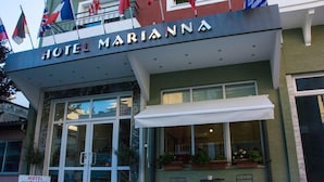 Un hotel llamado "Hotel Marianna" con una fachada moderna, ventanas amplias y un área de estar al aire libre.