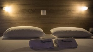 Una cama bien hecha con dos almohadas y dos toallas dobladas, con el nombre de marca "MARILANNA" en un cabecero de madera.
