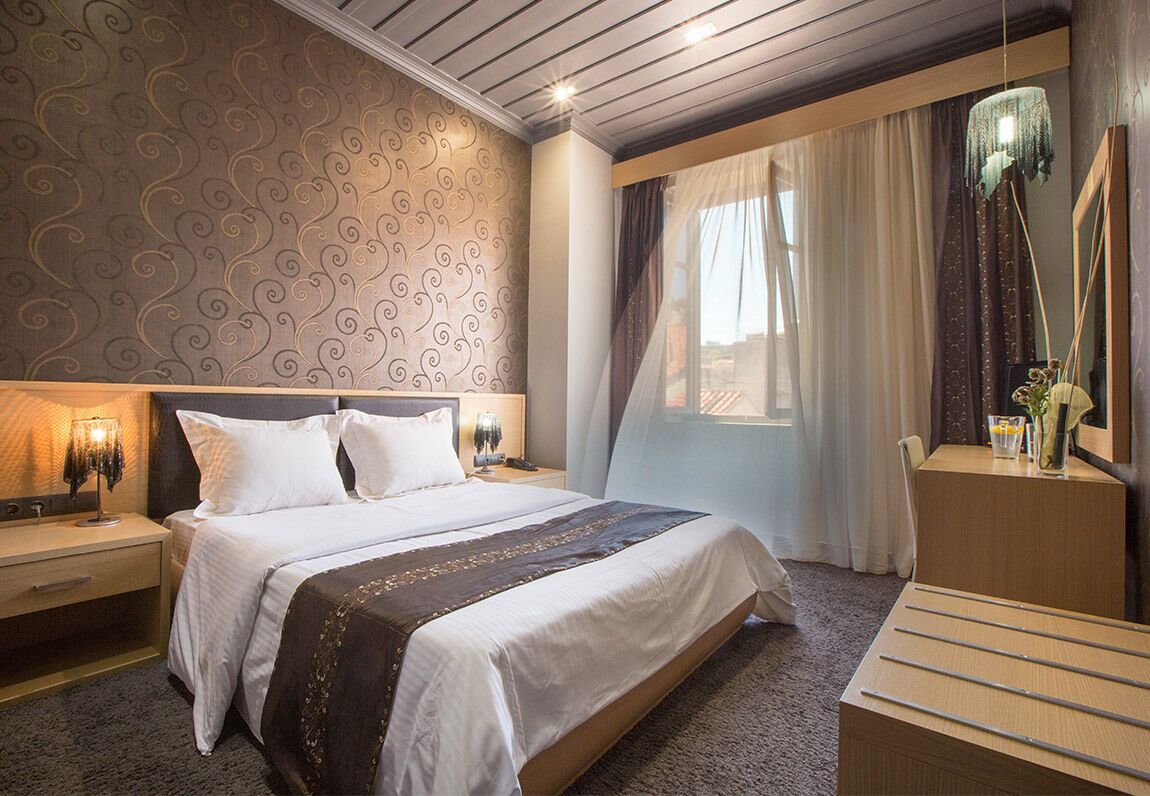 A hotel room with a large bed, bedside tables, a desk, and a mirror.