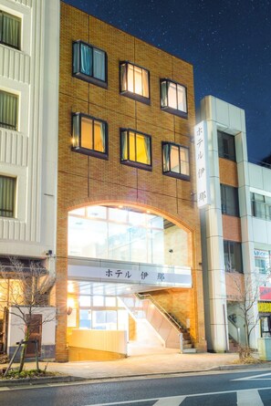 A hotel with a modern brick facade, large windows, and a visible entrance with a staircase.