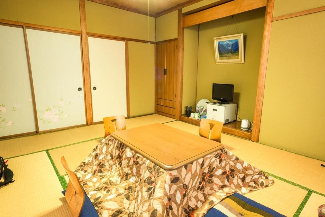 A traditional Japanese room with tatami flooring, a low table, and sliding doors.