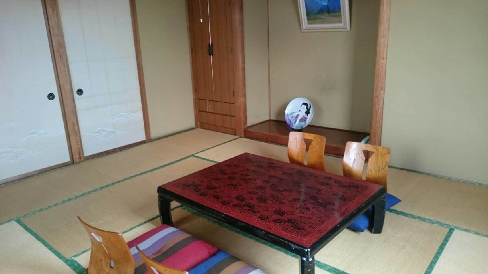A tatami mat room with a low table and four wooden chairs.