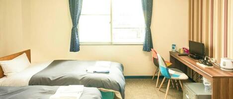 Une chambre d’hôtel avec deux lits, un bureau, une chaise et un téléviseur.