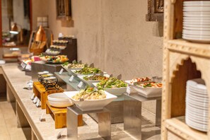A buffet with various dishes and a long serving counter. - Thousand Nights-Ash Sharqiyah Sands (Bidiya)