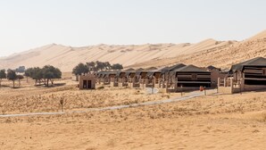 Un resort en el desierto con varias tiendas dispuestas en filas, un camino pavimentado y vegetación escasa.