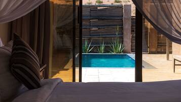 Un dormitorio con una cama grande, vistas a una piscina y una valla de madera en el exterior.