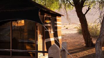 Une cabane rustique à l’extérieur rayé, avec une porte en bois et une lanterne.