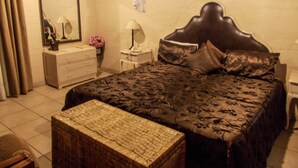 Un dormitorio con una cama grande, una mesita de noche, un aparador, un espejo y un dosel colgante.
