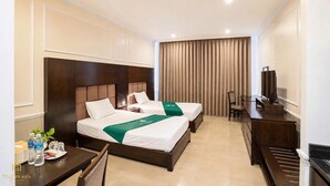 A hotel room with two beds, a desk, a chair, a television, and a curtain.