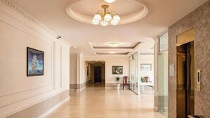 Un pasillo de hotel con candelabro, obras de arte enmarcadas y un mostrador de recepción.