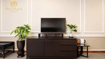 A modern hotel room with a dark wooden cabinet, a flat-screen TV, and two potted plants.